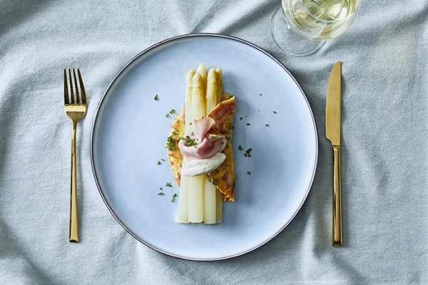 Gekookte witte asperges, geserveerd in omelet met ham 